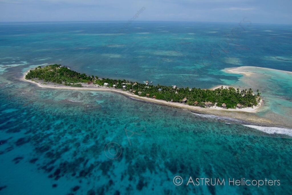 Aerial view of Long Caye at Glover’s Reef Atoll in Belize showing turquoise lagoon waters, coral reef systems, white sand shoreline, and eco-lodges along the island.