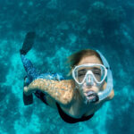 Woman snorkeling above coral reef at Lighthouse Reef Atoll Belize near Long Caye