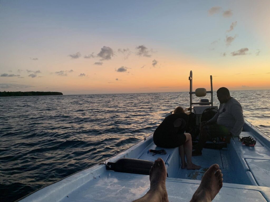 Boat returning across Lighthouse Reef Atoll at sunset in Belize after a day of diving