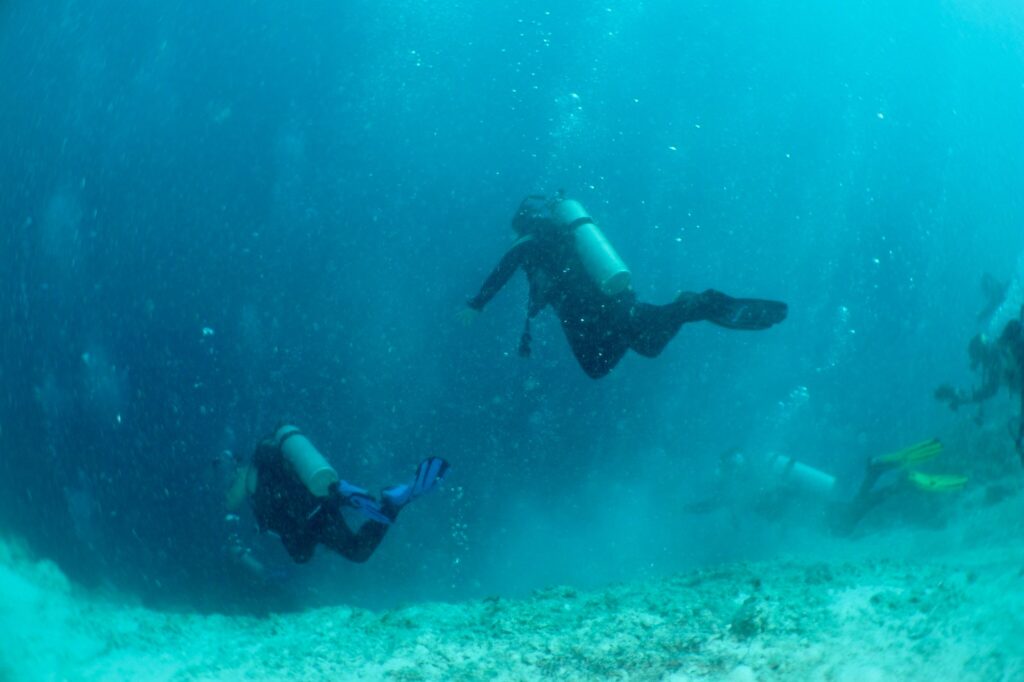 Scuba divers descending into the Great Blue Hole in Belize at Lighthouse Reef Atoll
