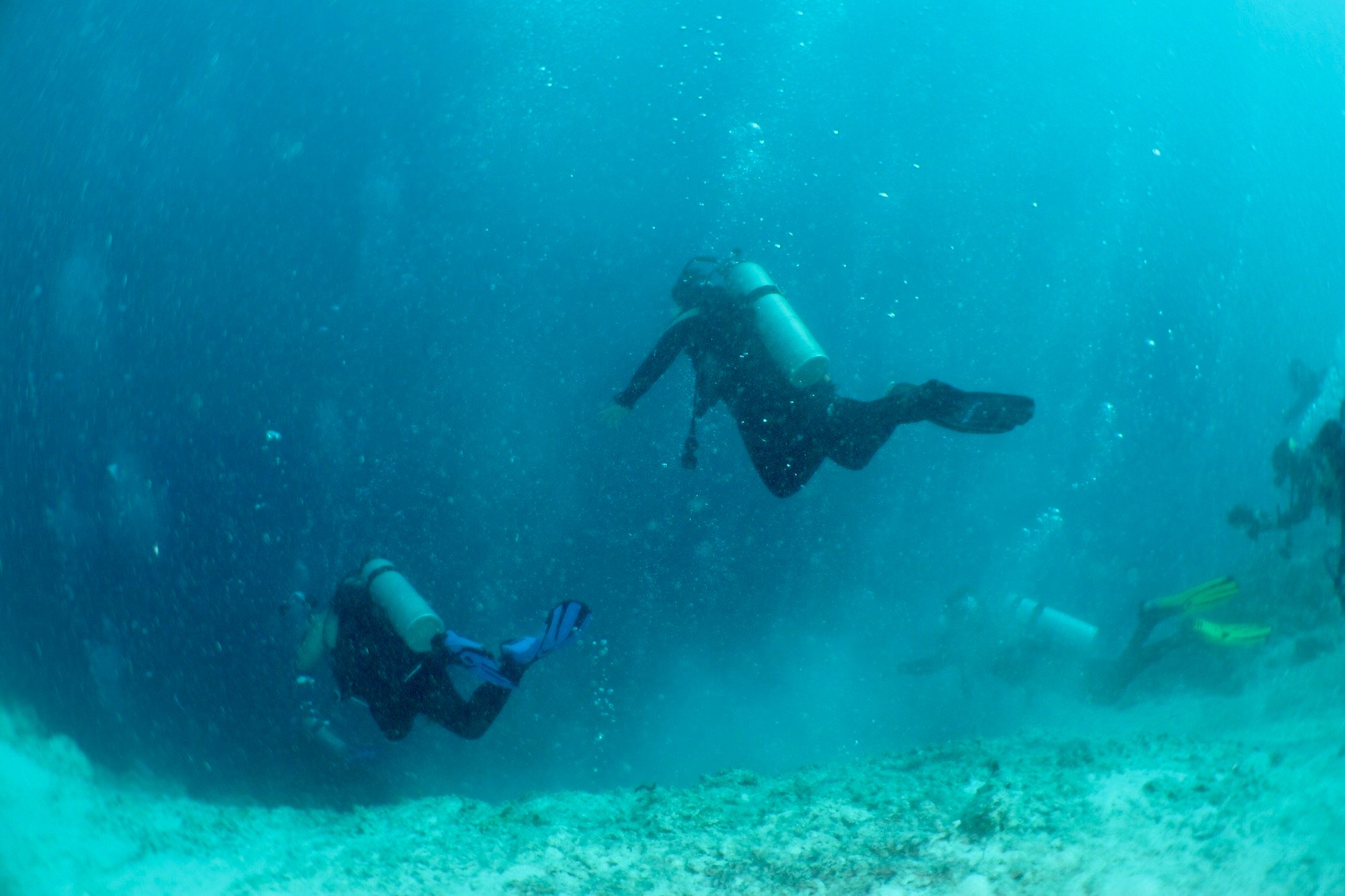 Scuba divers descending into the Great Blue Hole in Belize at Lighthouse Reef Atoll