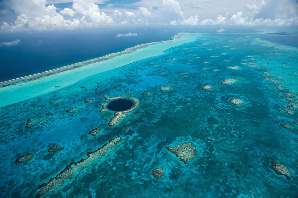 Aerial view of the Great Blue Hole at Lighthouse Reef Atoll in Belize showing deep blue sinkhole surrounded by coral reef and turquoise water