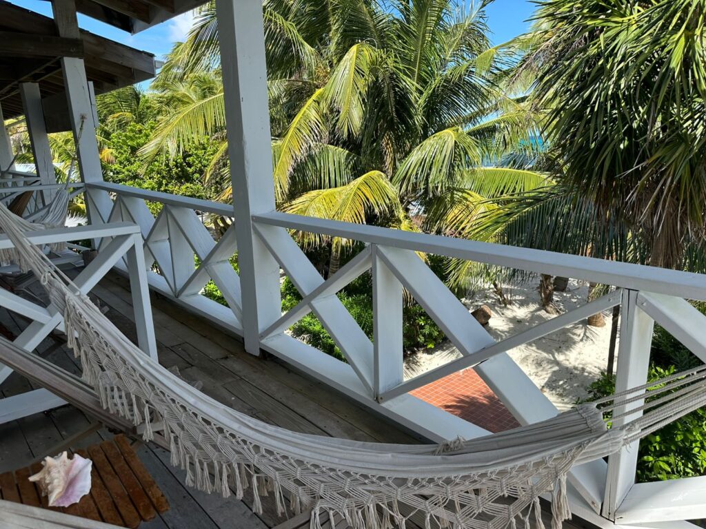 Private balcony with hammock at Itza Resort sky level room overlooking palm trees and Caribbean Sea on Lighthouse Reef Belize