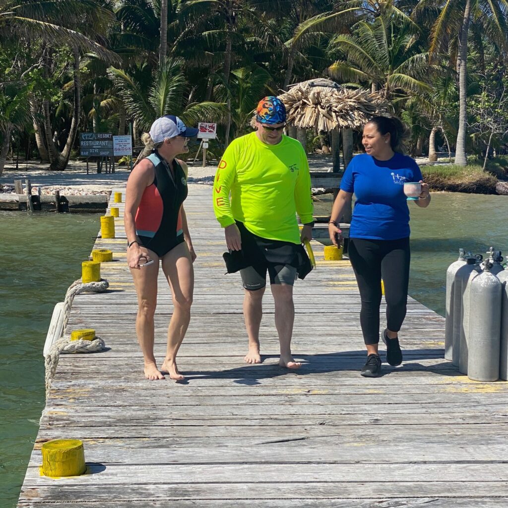Guests and staff walking along the dive dock at Itza Resort on Lighthouse Reef Atoll between dives in Belize