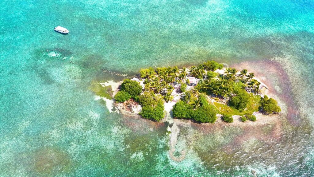 Aerial view of Hat Caye surrounded by turquoise water inside Lighthouse Reef Atoll, Belize.