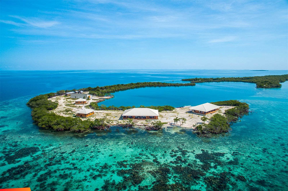 Small island known as Saddle Caye surrounded by shallow reef waters in Lighthouse Reef Atoll Belize.